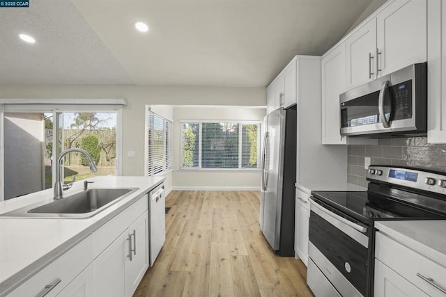 kitchen featuring tasteful backsplash, sink, white cabinetry, light wood-type flooring, and stainless steel appliances