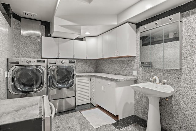 washroom featuring sink, tile walls, and washer and dryer