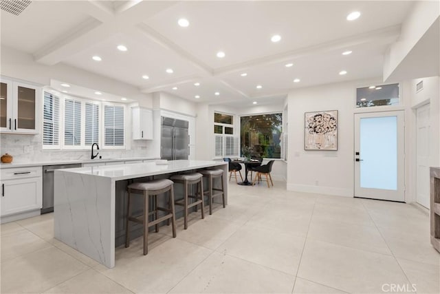 kitchen featuring white cabinetry, a large island, stainless steel appliances, a kitchen breakfast bar, and sink