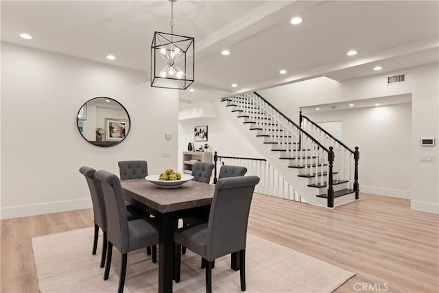 dining room with light wood-type flooring, beamed ceiling, and an inviting chandelier