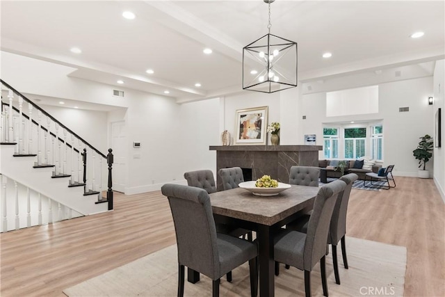 dining space featuring an inviting chandelier, beam ceiling, and light hardwood / wood-style floors