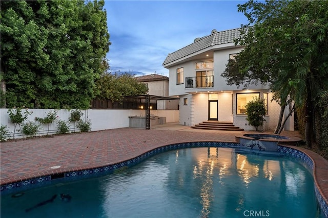 pool at dusk with an in ground hot tub and a patio