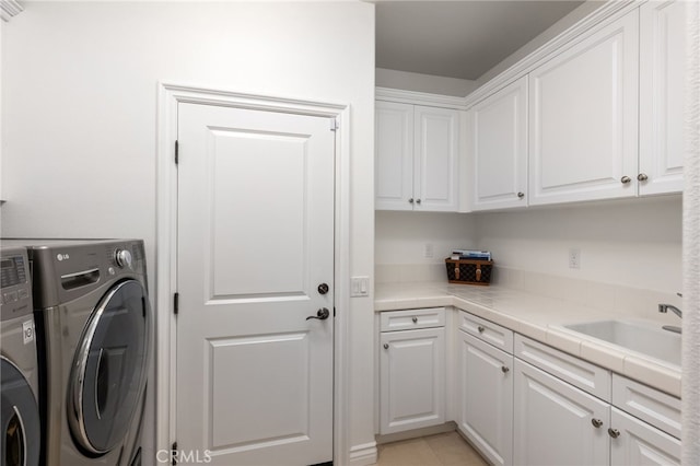 clothes washing area with cabinets, light tile patterned flooring, separate washer and dryer, and sink