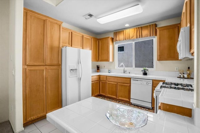 kitchen featuring tile countertops, light tile patterned flooring, white appliances, and sink