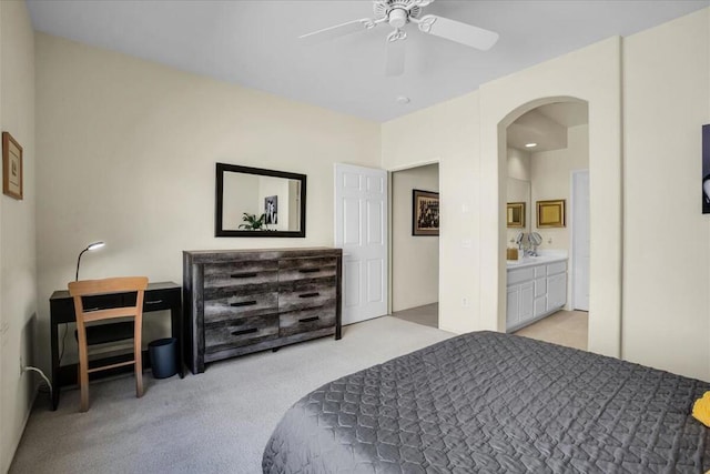 bedroom with ceiling fan, light carpet, and ensuite bath