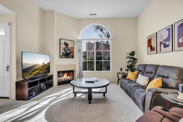 carpeted living room featuring a tiled fireplace