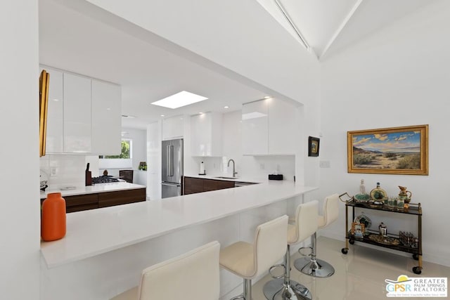 kitchen featuring white cabinets, a kitchen breakfast bar, sink, and stainless steel appliances