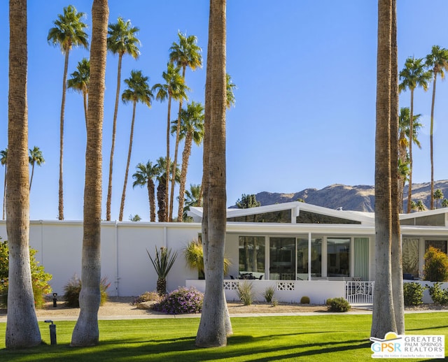 back of property with a mountain view and a yard