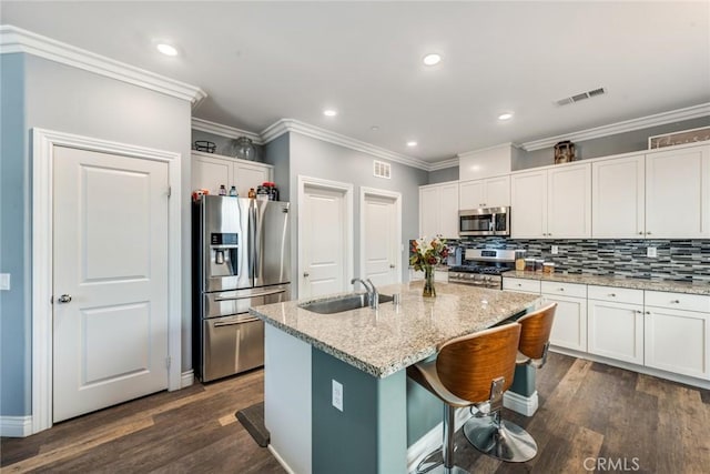 kitchen with a center island with sink, light stone counters, sink, and appliances with stainless steel finishes