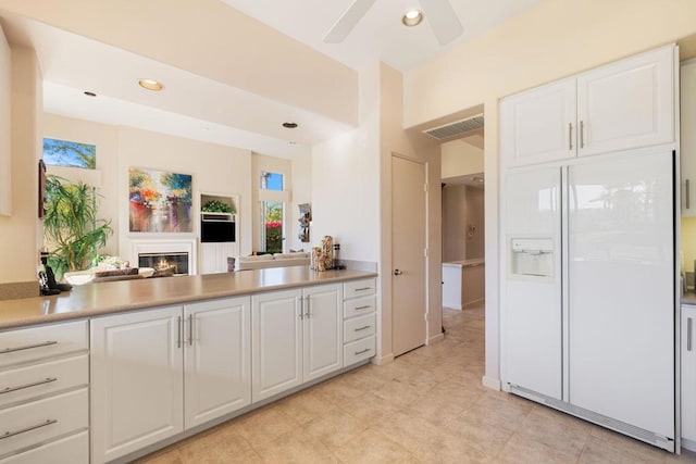 kitchen featuring ceiling fan, white cabinetry, and white fridge with ice dispenser