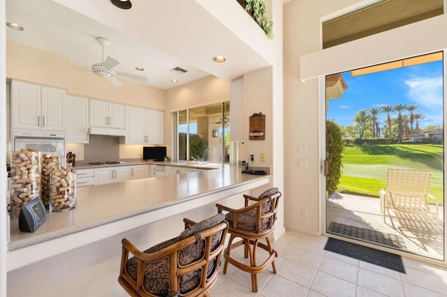 kitchen with white cabinets, oven, ceiling fan, light tile patterned floors, and kitchen peninsula