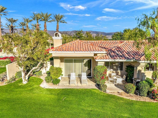 rear view of property featuring a mountain view, a yard, and a patio area