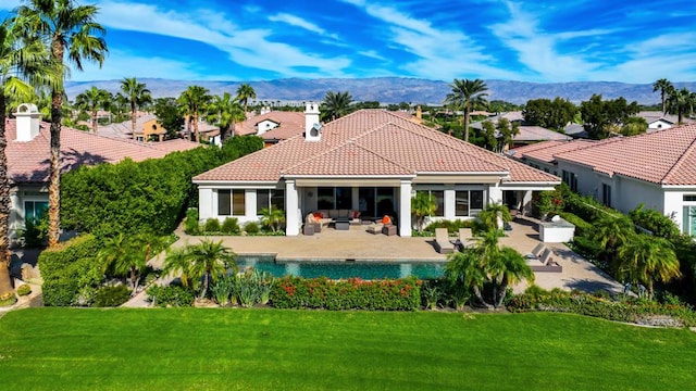 rear view of property with a mountain view, an outdoor hangout area, a patio, and a lawn