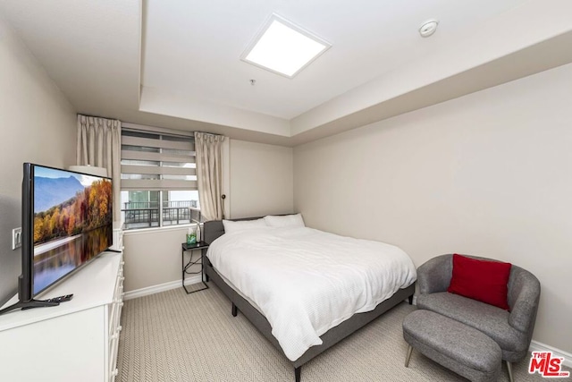 bedroom featuring a raised ceiling and light carpet