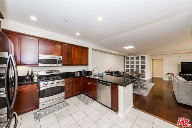 kitchen with kitchen peninsula, appliances with stainless steel finishes, light tile patterned flooring, and sink