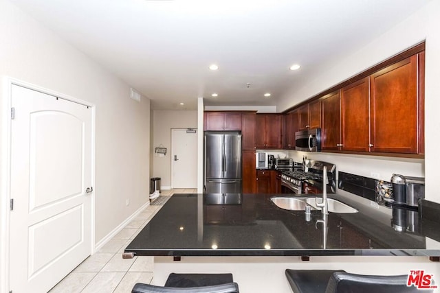 kitchen featuring a breakfast bar, sink, light tile patterned floors, kitchen peninsula, and stainless steel appliances