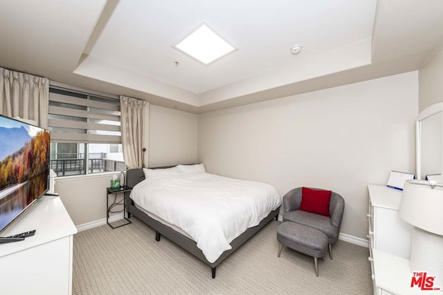 bedroom with light colored carpet and a raised ceiling