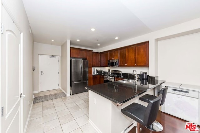 kitchen with sink, light tile patterned flooring, a kitchen bar, kitchen peninsula, and stainless steel appliances