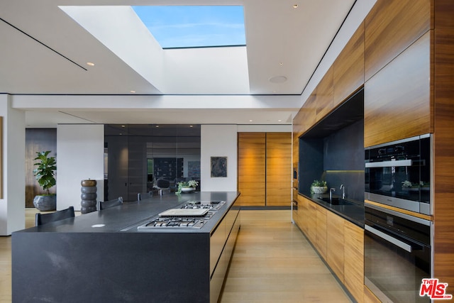 kitchen featuring a skylight, sink, a center island, and stainless steel gas cooktop