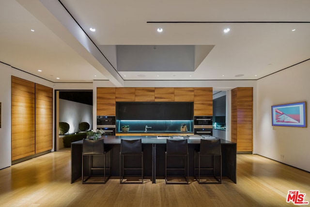 kitchen with a kitchen breakfast bar, light hardwood / wood-style floors, a spacious island, and oven