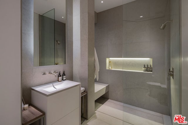 bathroom featuring tile patterned floors, vanity, tile walls, and walk in shower