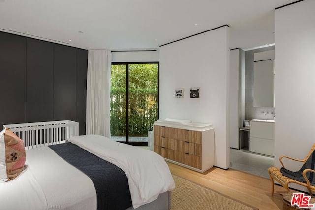 bedroom with access to exterior, ensuite bathroom, and light wood-type flooring