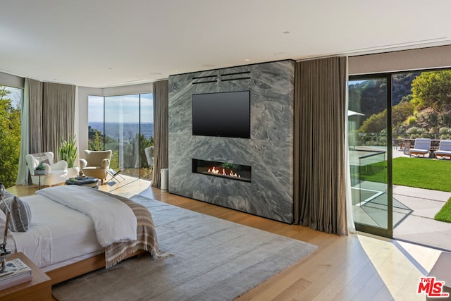 bedroom with light hardwood / wood-style floors, a fireplace, and access to outside