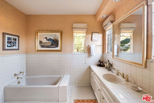 bathroom with tile patterned floors, vanity, a tub to relax in, and tile walls