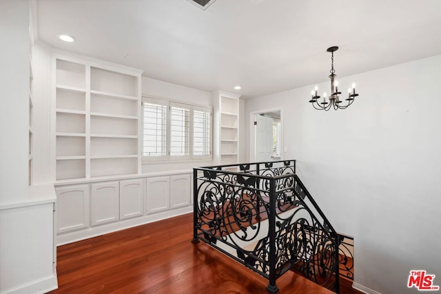 hallway with dark wood-type flooring and a notable chandelier