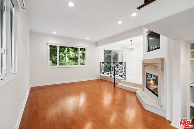 unfurnished living room featuring a fireplace, hardwood / wood-style floors, and a chandelier