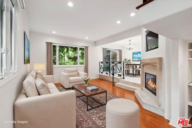 living room featuring hardwood / wood-style flooring, a notable chandelier, and a fireplace