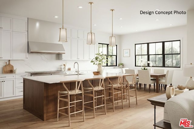 kitchen with custom exhaust hood, a breakfast bar, a kitchen island with sink, sink, and white cabinets