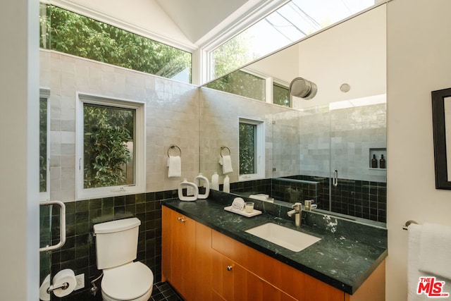 bathroom with tile patterned floors, vanity, vaulted ceiling, tile walls, and toilet