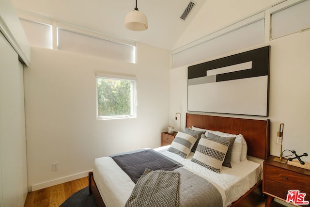 bedroom with wood-type flooring and vaulted ceiling