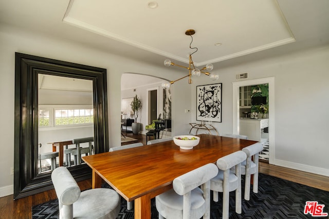 dining area featuring a raised ceiling, dark hardwood / wood-style floors, and an inviting chandelier