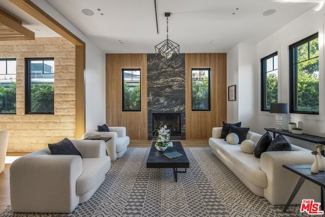 living room featuring a high end fireplace, hardwood / wood-style floors, and wooden walls