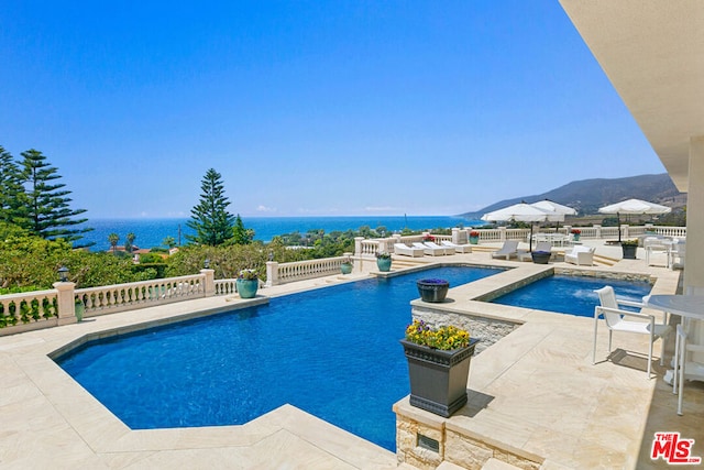 view of swimming pool with a water and mountain view and a patio