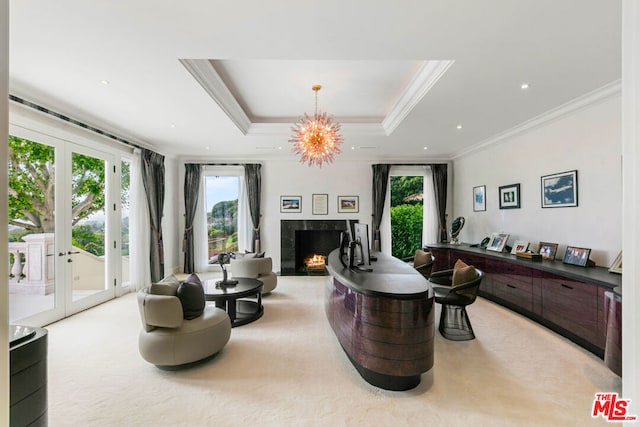 sitting room featuring a raised ceiling, a premium fireplace, a notable chandelier, crown molding, and light colored carpet