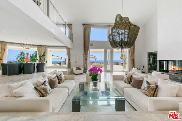 living room with a multi sided fireplace, a towering ceiling, and a chandelier