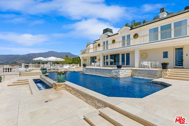 view of swimming pool with a patio area, a mountain view, and pool water feature