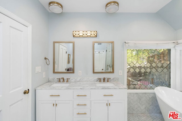 bathroom with vanity, a tub, and vaulted ceiling