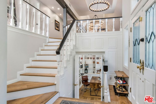 staircase with a barn door, hardwood / wood-style floors, and a notable chandelier