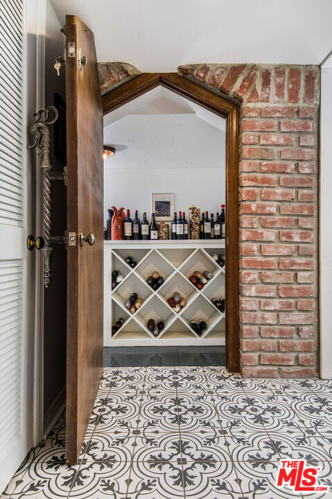 wine room with light tile patterned floors and brick wall