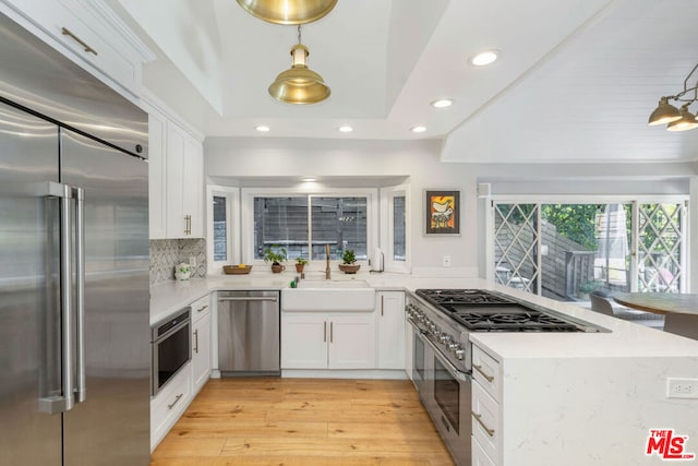 kitchen with white cabinets, pendant lighting, high end appliances, and backsplash