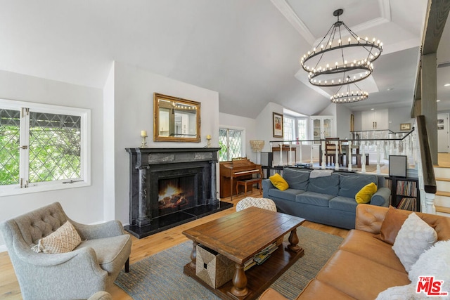 living room featuring hardwood / wood-style floors, ornamental molding, a high end fireplace, and a chandelier