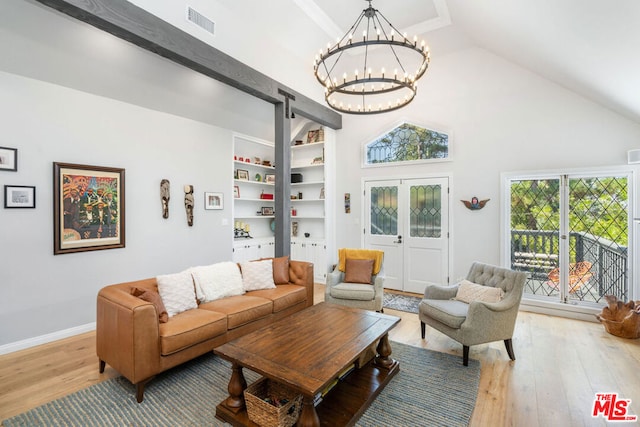 living room featuring a barn door, built in shelves, light hardwood / wood-style flooring, and a notable chandelier