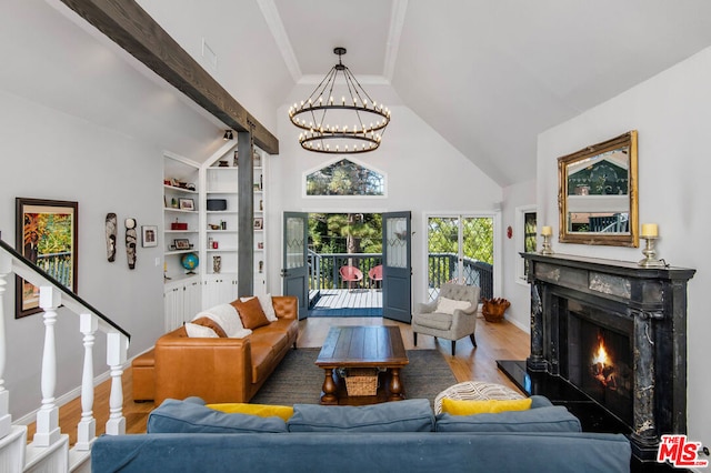 living room with a high end fireplace, built in shelves, vaulted ceiling, hardwood / wood-style flooring, and a chandelier