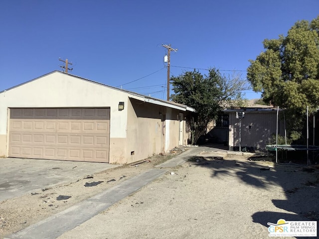 view of side of property featuring an outbuilding, a garage, and a trampoline