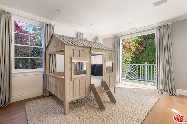 bedroom with access to exterior, hardwood / wood-style flooring, multiple windows, and ornamental molding