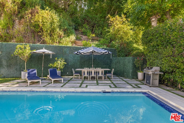 view of pool featuring grilling area and a patio